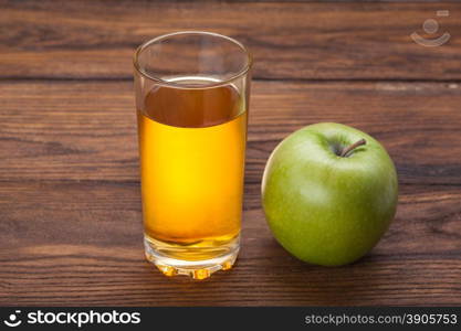Glass of apple juice and green apple on wooden background