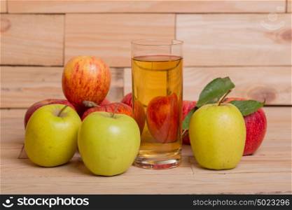 Glass of apple juice and red apples on wooden background