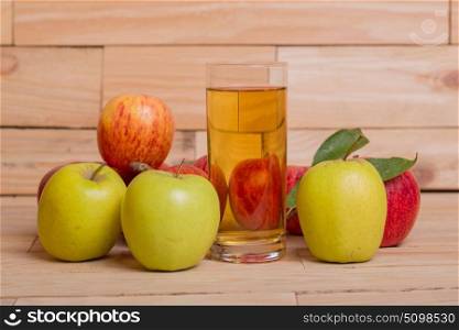Glass of apple juice and red apples on wooden background