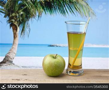 Glass of apple juice on a beach table
