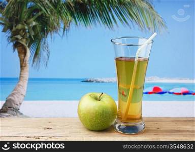 Glass of apple juice on a beach table