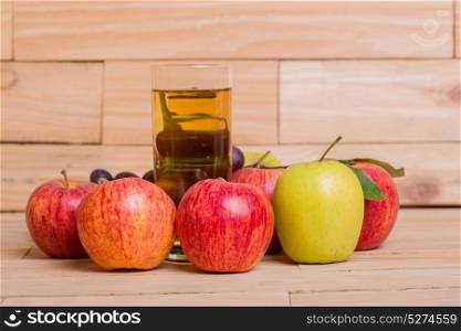 Glass of apple juice with fruits on wooden background