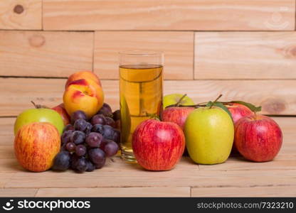 Glass of apple juice with fruits on wooden background