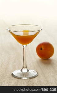 Glass of apricot liqueur and fresh fruit on the background