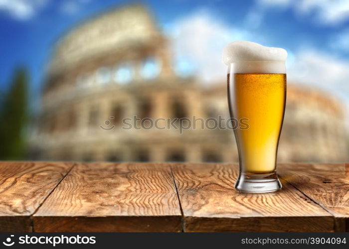 Glass of beer against Colosseum. Glass of beer on wooden table with Colosseum in Rome on background with natural bokeh