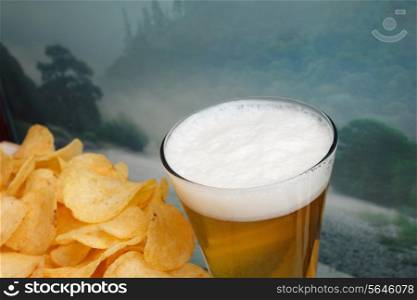 glass of beer and potato chips in a landscape