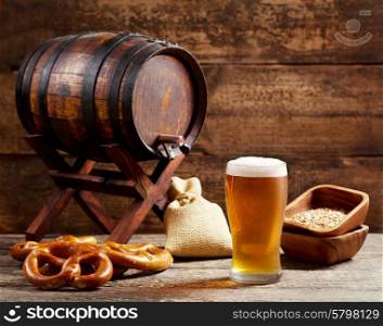 glass of beer with barrel on wooden background