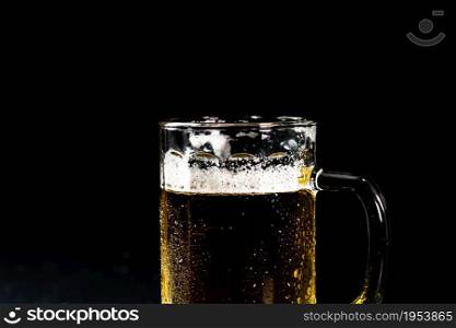 Glass of beer with beer foam on dark background