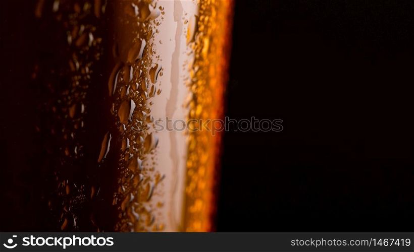 Glass of beer with foam on black background closeup. copy space on right. Glass of beer with foam on black background closeup