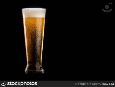 Glass of beer with foam on black background. copy space on right. Glass of beer with foam on black background
