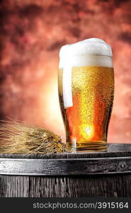 Glass of beer with wheat ears on a wooden barrel. Glass of beer with wheat ears