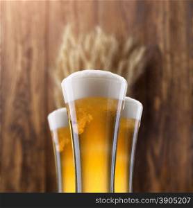 Glass of beer with wheat on wooden background