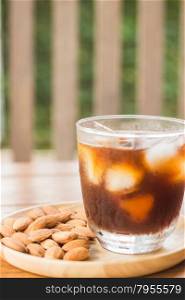 Glass of black iced coffee with almond grain, stock photo