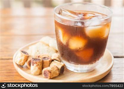 Glass of black iced coffee with some snack, stock photo