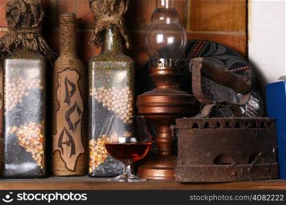 Glass of brandy standing on a fireplace shelf with various vintage objects