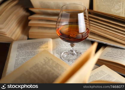 Glass of brandy standing on open books