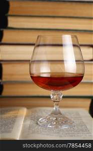 Glass of brandy standing on open books