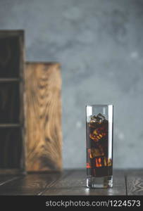 Glass of brew cold coffee and ice. Cold summer drink on a dark wooden table and gray background with copy space.