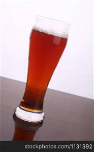 Glass of brown ale over a white background