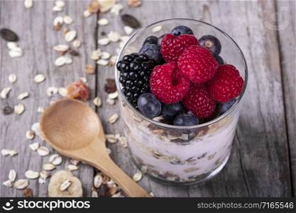 glass of cereal with fruits of the forest, on a wooden base. concept of healthy breakfast