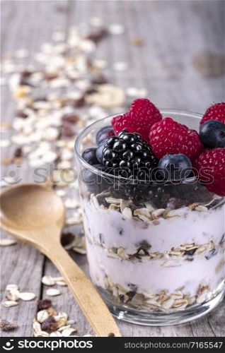 glass of cereal with fruits of the forest, on a wooden base. concept of healthy breakfast