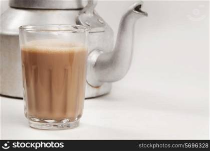 Glass of chai with an old fashioned kettle isolated over white background