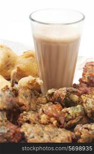 Glass of chai with pakoras , bhajiyas and fried potato balls isolated over white background