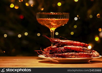 glass of champagne and shrimp on a Christmas tree background. festive atmosphere.. glass of champagne and shrimp on a Christmas tree background. festive atmosphere