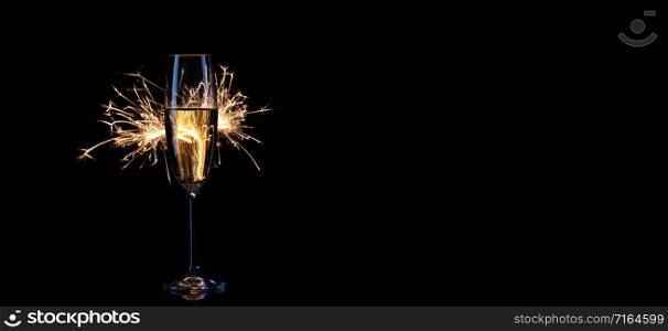 Glass of champagne and sparklers on a black background. Concept for celebrating Christmas, New Year and other celebrations.. Glass of champagne and sparklers on black background