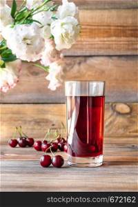 Glass of cherry juice with fresh cherries on the wooden background