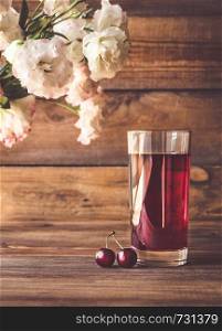 Glass of cherry juice with fresh cherries on the wooden background