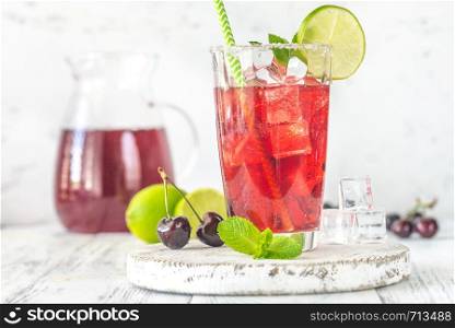Glass of cherry mojito garnished with lime slice