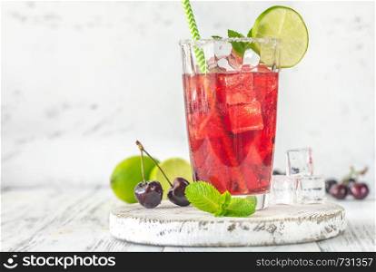 Glass of cherry mojito garnished with lime slice