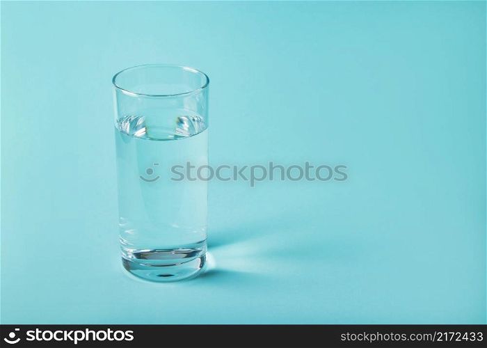 Glass of clear water on a blue background. Health concept, place for text.. Glass of clear water on a blue background. Health concept.