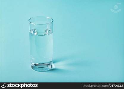 Glass of clear water on a blue background. Health concept, place for text.. Glass of clear water on a blue background. Health concept.