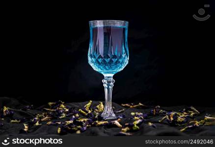 Glass of Cocktail butterfly pea or Flower anchan blue juice (Clitoria) and dry butterfly pea flowers on dark background. Healthy detox herbal drink, space for text, Selective focus.