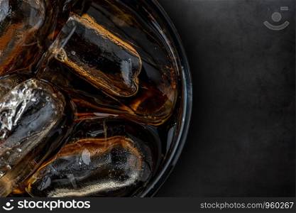 Glass of coke with ice cubes on dark stone background. Coke with ice