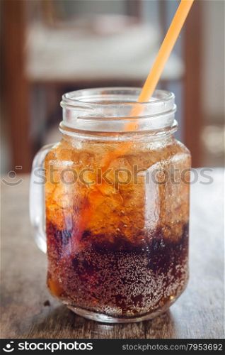 Glass of cola with ice on wooden table, stock photo