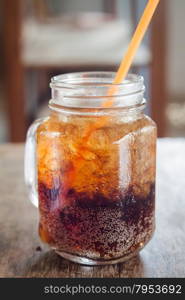 Glass of cola with ice on wooden table, stock photo