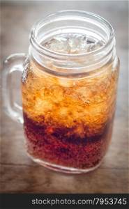Glass of cola with ice on wooden table, stock photo