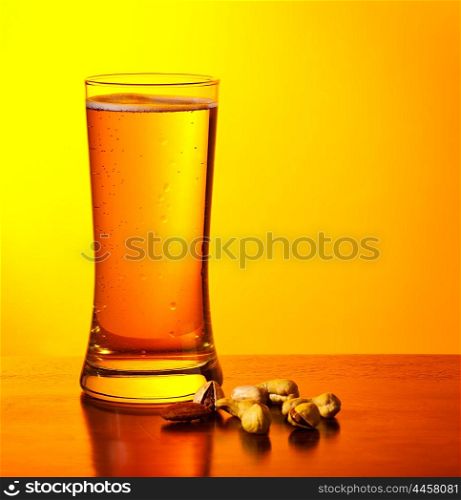 Glass of cold beer drink and nuts isolated on yellow warm background, festival of beer, oktoberfest autumn holiday