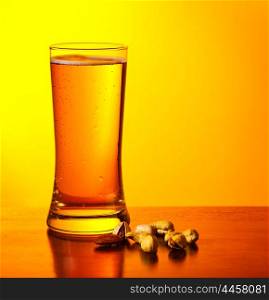 Glass of cold beer drink and nuts isolated on yellow warm background, festival of beer, oktoberfest autumn holiday