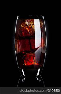 Glass of cold cola soda drink with ice cubes on black background