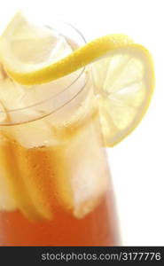 Glass of cold lemon iced tea with ice, lemon and water drops on glass surface