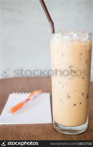 Glass of cold milk coffee on wooden table, stock photo