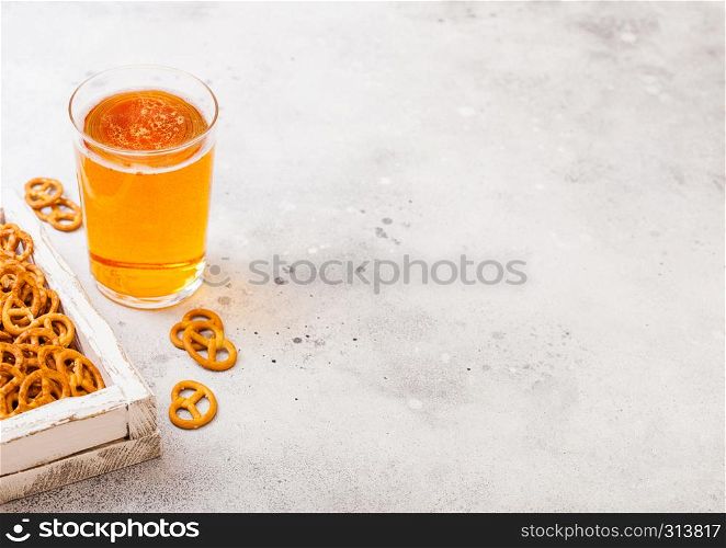 Glass of craft lager beer with pretzel snack in vintage wooden box and opener on stone kitchen background. Beer and snack.