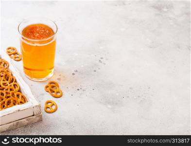 Glass of craft lager beer with pretzel snack in vintage wooden box and opener on stone kitchen background. Beer and snack.