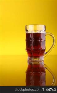 Glass of dark beer over a bright yellow background