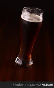 Glass of dark beer over a dark background