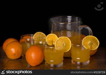 glass of delicious orange juice with oranges on a table, studio picture